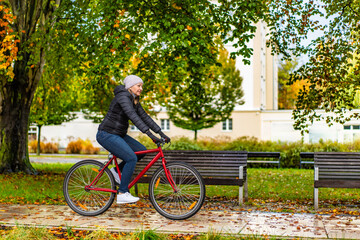 Mid-adult woman riding bicycle in city park on a rainy day 