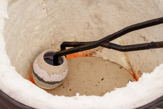 Glazed Raku bisqueware is carefully loaded into a special gas fired kiln, using metal tongs, where is will be heated rapidly until glowing red hot
