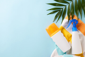 Summer vacation preparation with sunscreen and beach towel on a pastel blue background