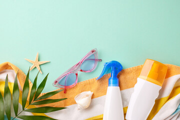 Top view summer vacation concept with sunscreen, sunglasses, and towel on a turquoise background