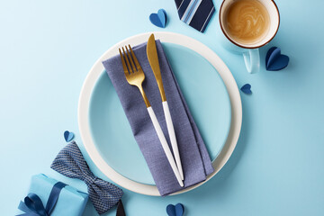 Father's day dining decor concept. Top view of table setting with cutlery and gift on a soft blue...