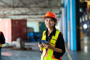 A woman wearing a safety vest and holding a clipboard in the large warehouse warehouse.