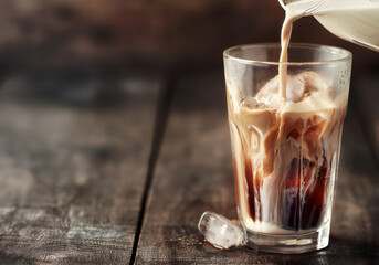Iced coffee in glass on wooden background