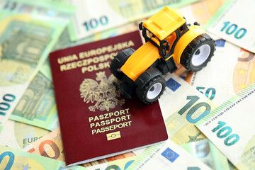 Red polish passport and yellow tractor on euro money bills close up - obrazy, fototapety, plakaty