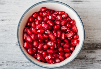 Juicy organic pomegranate seeds in a bowl, centered.