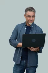 Foto auf Glas Casual mid adult man standing holding laptop computer. Portrait of happy middle aged male in 50s with gray hair and glasses, smiling. Isolated on white background. © nyul