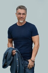 Portrait of mid adult, older, gray hair man in glasses. Male in casual and jeans standing isolated on gray background. Happy confident smile. - 783945718