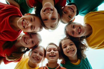 Children's group hugging and laughing, looking down at the camera from below