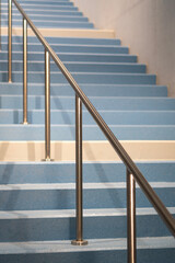 Light blue staircase with gray metal railing in a building