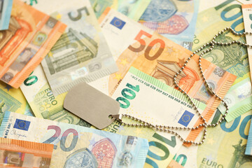 Many European euro money bills and dogtags. Lot of banknotes of European union currency and military medallion close up