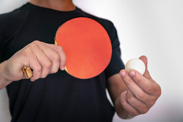 Hands holding ping pong racket and ball on white background.
