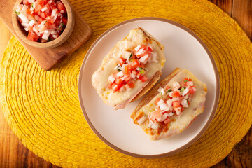 Molletes. Mexican recipe based on bolillo bread split lengthwise, spread with refried beans and gratin cheese, adding pico de gallo sauce and some protein such as ham, bacon or chorizo. - 783961722