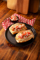 Molletes. Mexican recipe based on bolillo bread split lengthwise, spread with refried beans and gratin cheese, adding pico de gallo sauce and some protein such as ham, bacon or chorizo.