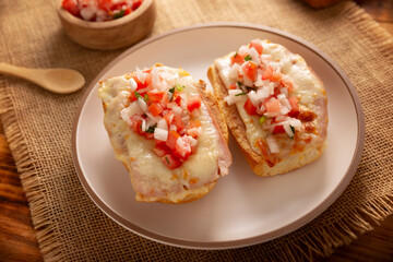 Molletes. Mexican recipe based on bolillo bread split lengthwise, spread with refried beans and gratin cheese, adding pico de gallo sauce and some protein such as ham, bacon or chorizo. - 783962199
