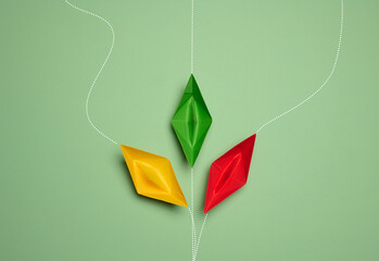 Paper boats on a green background with paths of movement, representing the concept of individuality