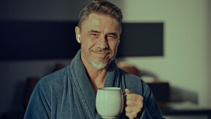 Casual older man in bathrobe at home drinking morning coffee. Portrait of happy mid adult male with confident smile.