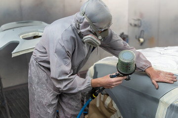 Auto Painter Spraying Paint on Car in Workshop