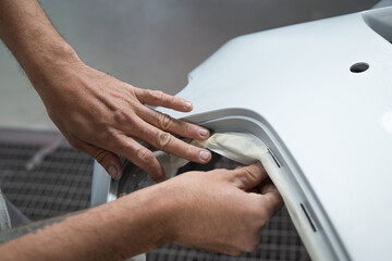 Hands Applying Tape on Car Body for Painting