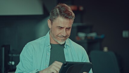 Man working on tablet computer in office, looking at screen. Portrait of mid adult busy businessman...