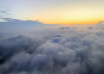 Aerial view of fluffy white clouds and a distant sunset