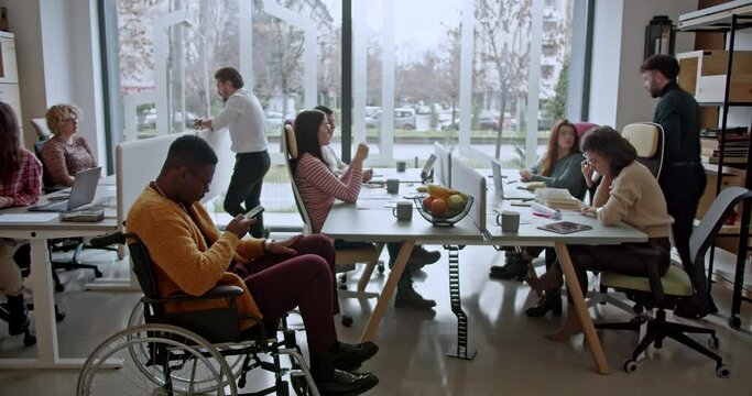 A group of colleagues is engaged in a focused discussion about a new project in an accessible office setup, showcasing teamwork and dedication towards their shared goals.