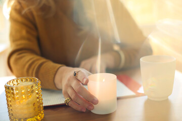 Blurred image of woman lightning scented candle while working remotely at home