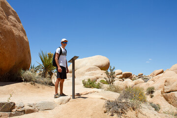 Man stands next to information stand on the Arch Rock trail stand. Travel and adventure concept....