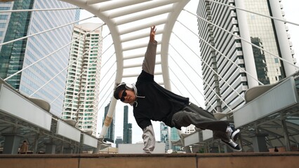 Young asian hipster show footstep at city center surround by people. Stylish fashion street dancer perform B-boy or freestyle dancing with low angle. Outdoor sport 2024. Break dancing. Sprightly.