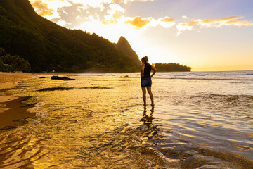 Sunset Reflection on Female Tourist Standing in Tide Pools at Tunnels Beach, Kauai, Hawaii, USA