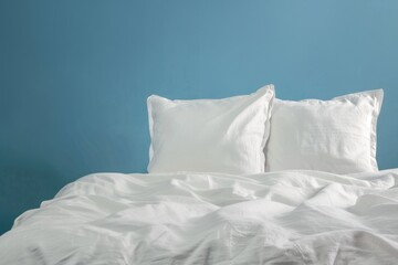 Fototapeta na wymiar Bed with white pillows against blue wall