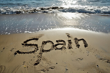 Spain written in the sand on a beach. Spanish tourism and vacation background - 783987349