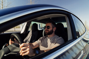 Man in sunglasses driving an electric car, showcasing a sustainable and eco-friendly lifestyle with...