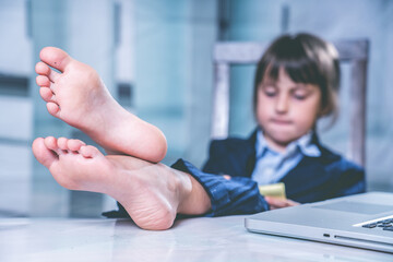 Business child girl working and resting at the same time. Selective focus on bare feet. Horizontal...