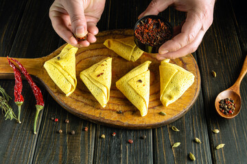 Chef preparing pancakes at home on a kitchen board. Hands with spices at the final stage of...