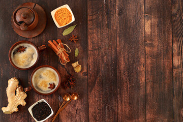 Indian masala chai tea with milk, ginger, anise and cinnamon on an old wooden table. Traditional drink with spices, cafe concept, advertising for restaurant and menu