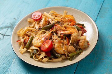 shrimp and udon vegetables pad thai sauce on a blue table. copy space