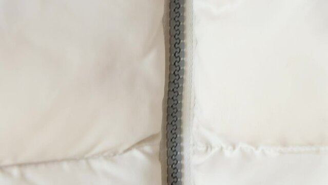 White puffy winter jacket and zipper as a background close-up, white 