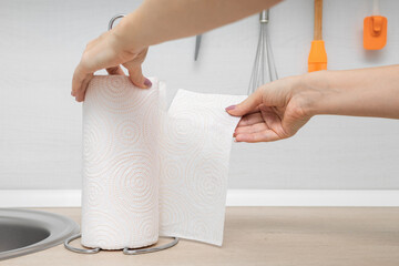 housewife in the kitchen tears off a paper towel.