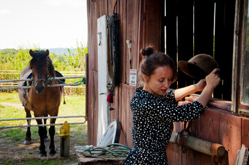 Woman with horse in stable at countryside ranch. Girl horse rider in summer outdoor. Equestrian and...
