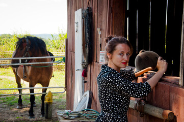 Woman with horse in stable at countryside ranch. Girl horse rider in summer outdoor. Equestrian and...