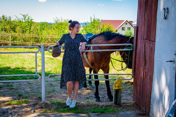 Woman with horse in stable at countryside ranch. Girl horse rider in summer outdoor. Equestrian and...