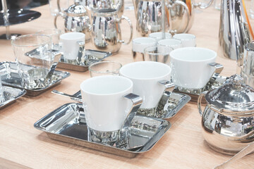 A table full of silverware and cups, including a teapot and a cup. The table is set for a special...