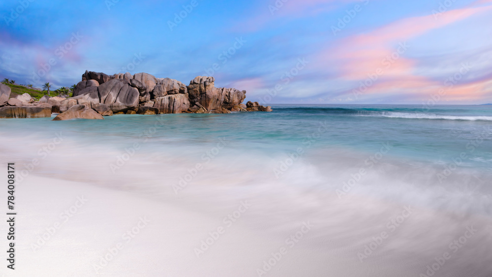 Poster a rocky shoreline with a calm ocean in the background. the sky is a mix of blue and pink, creating a