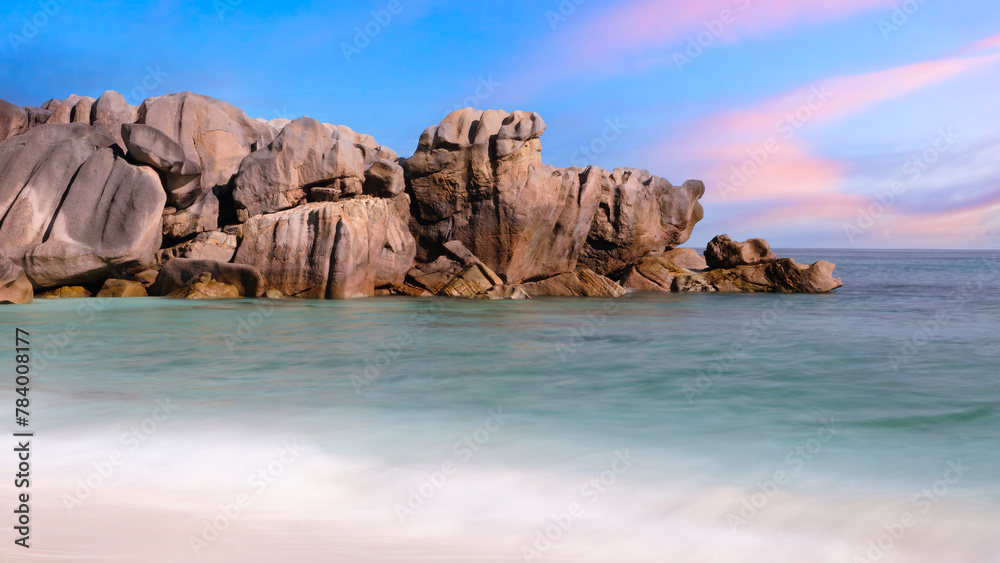 Poster a rocky shoreline with a calm ocean in the background. the sky is a mix of blue and pink, creating a