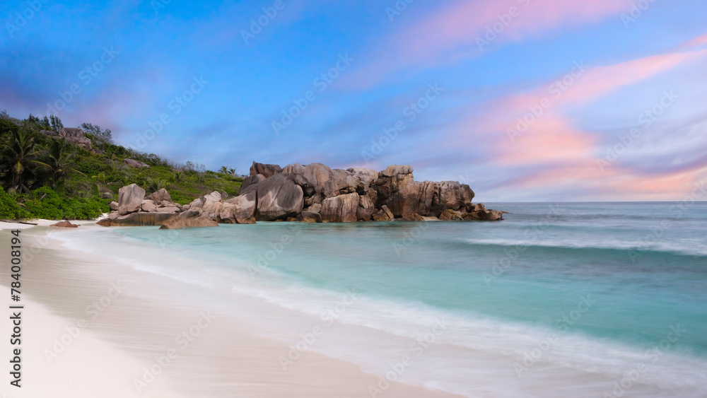 Poster a rocky shoreline with a calm ocean in the background. the sky is a mix of blue and pink, creating a
