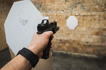 Shooting from a tactical pistol at targets in a shooting range, first-person photo view.