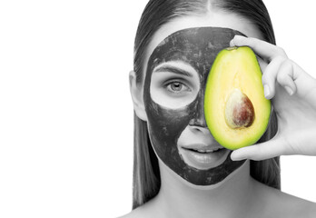 Beautiful smiling woman with clear skin holds a ripe avocado near her face. She applied the mask to her face. Cosmetological skin care