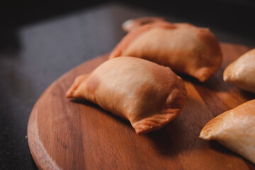 Detail view of a fried empanada on a circular wooden tray.