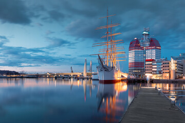 Waterfront with historic sailing ship in Gothenburg, the iconic Lilla Bommen building with night...
