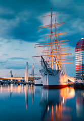 A historic sailing ship moored at Gothenburg's waterfront, with the iconic Lilla Bommen building...